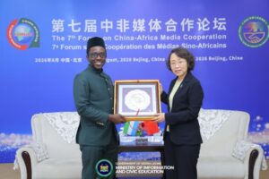 | The Calabash Newspaper Two officials exchange a framed award on a blue conference backdrop reading 'The 7th Forum on China-Africa Media Cooperation'.