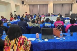| The Calabash Newspaper Participants at a community workshop seated around blue-tablecloth tables in a conference room, with laptops and water bottles visible.