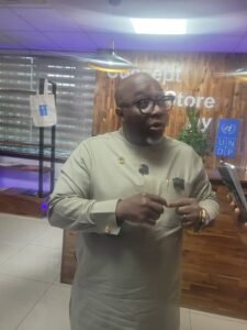 UNDP Sierra Leone Resident Representative, Fredrick Ampiah | The Calabash Newspaper Man in beige traditional attire with glasses speaks into a lapel mic in front of a wooden background with UNDP branding in view.
