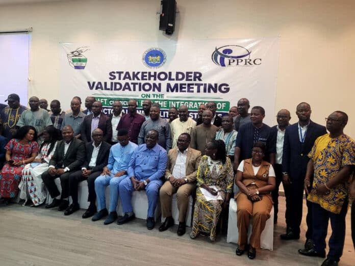 Diverse group of people posing for a photo at a stakeholder validation meeting with a banner behind them displaying the event title.