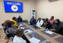NMA, ACC Train New Mining Staff on Ethics and Integrity Group of professionals seated around a long conference table in a meeting room, a blue 'WELCOME' screen on the wall behind them, laptops and water bottles on the table.