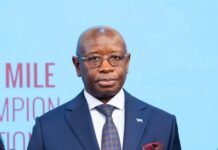Sierra Leone Increases IFAD14 Contribution by 50% as President Bio Prioritizes Agriculture and Rural Development Man in a navy suit and patterned tie stands before a light blue backdrop.