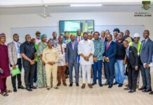 IPAM Commissions New Banking Facilities, Modern Lecture Rooms for Master’s Students Group of diverse professionals posing for a photo in a classroom at The University of Sierra Leone logo visible on the wall.