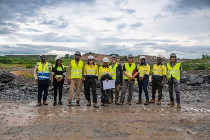 Group of construction workers in neon vests and hard hats standing in a rocky quarry.