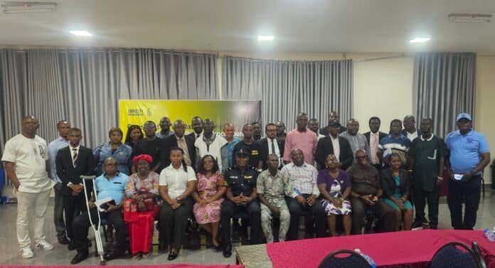 Group of diverse men and women posing for a formal photo in a conference room, with a yellow Amnesty International banner in the background.