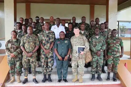 Group photo of soldiers and officers in camouflage uniforms standing on the steps of a building in formation.