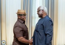 As ECOWAS Praises Sierra Leone… Bio–Koroma Meeting Sends Strong Message of Peace and Unity Two older men shake hands and smile in a room with cream curtains; one wears a brown shirt and straw hat, the other in a dark blue traditional outfit.