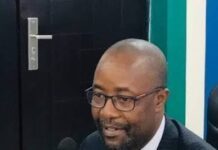 Visa Documentation Scandal: Foreign Ministry Sets Up Internal Investigative Committee Man in a dark suit and tie, wearing glasses, speaking into a microphone at a desk during a formal meeting.