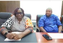 NMA, ACC Strengthen Workplace Ethics and Anti-Corruption Compliance Two adults sit at a conference table in a meeting room, the woman in a patterned blouse and glasses and the man in a blue traditional outfit.
