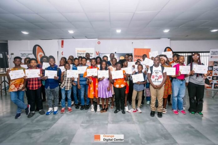Group of children posing with certificates at an Orange Digital Center event ceremony in a bright hall.