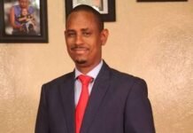 Chericoco Emerges as Unifying Trailblazer and Strong Choice to Lead APC to State House in 2028 Man in a navy suit and red tie posing with hands clasped in front.