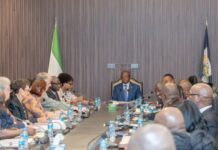 At DEPAC Meeting, President Bio Calls for Urgent Action on Census Funding and National Priorities Formal meeting with a man in a blue suit at the head of a long conference table, surrounded by delegates, flags behind him.