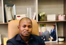 SALHOC Calls for Thorough Probe After Vandals Target Corporation’s Office Man seated at a desk in an office, looking at the camera while holding a yellow document or folder in his right hand.