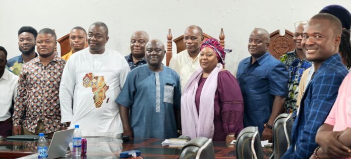 Group of people standing around a conference table in a meeting room, smiling at the camera.