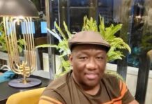 As He Challenges SLPP Membership Directive, Cites 2018 CDP Resignation Letter… Hon. Musa Tarawally: “I Am a Fully Paid-Up SLPP Member and Delegate” Smiling man in a brown and orange striped shirt and flat cap sits at a cafe table with plants in the background.