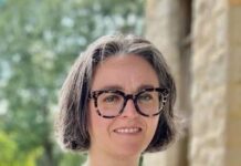 Sierra Leone Urban Research Takes Centre Stage in New African Cities Review Smiling woman with short gray hair and glasses standing outdoors beside a stone wall.