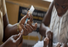 MoH Vaccinates 7,117 Zero-Dose Children as 300 Days Activism Hits 79% Target Healthcare workers administer a vaccine to a baby during a clinic visit, with one person holding the baby and another preparing a syringe.