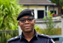 CP Abdul Moijue Commended for Visible Leadership in Freetown Traffic Management Portrait of a Sierra Leone police officer in navy uniform and beret, standing outdoors with greenery in the background.