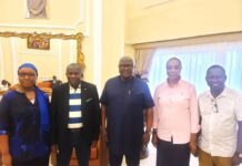Former President Koroma, Peace Commission Discuss Collaboration on Peace and National Cohesion Group of five adults posing for a photo in a bright, formal room with ornate decor in the background; they smile at the camera and stand side by side, dressed in smart casual to semi-formal attire.