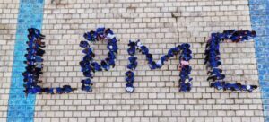 Aerial view of people in blue shirts standing on a stone plaza to form the word 'LOVE'.