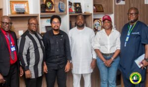 Six professionals pose for a group photo in an office with awards on shelves behind them.