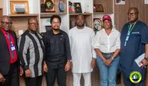 Six professionals pose for a group photo in an office with awards on shelves behind them.