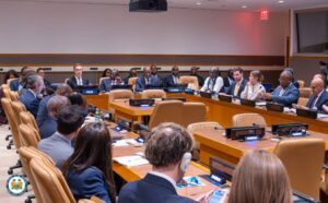 Diplomats and officials seated around a large conference table in a formal plenary meeting.