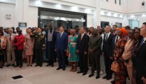 A diverse group of people in formal attire standing together for a group photo at an indoor event venue.