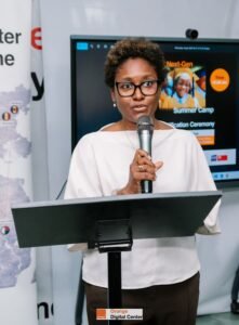 | The Calabash Newspaper Speaker with glasses addressing an audience at a podium; presentation screen behind reads 'Next-Gen Summer Camp'.