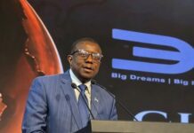 Labour Minister Woos Indian Investors, Champions Sierra Leone–India Economic Partnership Man in a blue pinstripe suit speaks at a podium with a microphone and a large screen showing a 'Big Dreams' logo behind him.