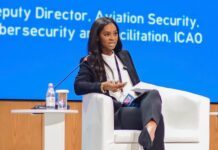 At ICAO Security Week in Kazakhstan… SLCAA DG Musayeroh Barrie Calls for Stronger Aviation Security Investment Woman panelist in a dark suit speaks into a microphone on stage, with a white chair, small table, and water bottle nearby.