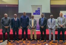 Government, UNCDF and Financial Institutions Explore New Investment Opportunities Under Feed Salone Seven men in formal attire stand in a row on a red-carpeted stage, with UNCDF banners in the background.