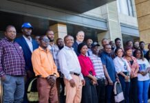 UNDP Empowers 20 Sierra Leonean Innovators to Turn Plastic Waste into Business Opportunities Group of diverse professionals posing together outside a modern building, smiling for a team or community event photo.