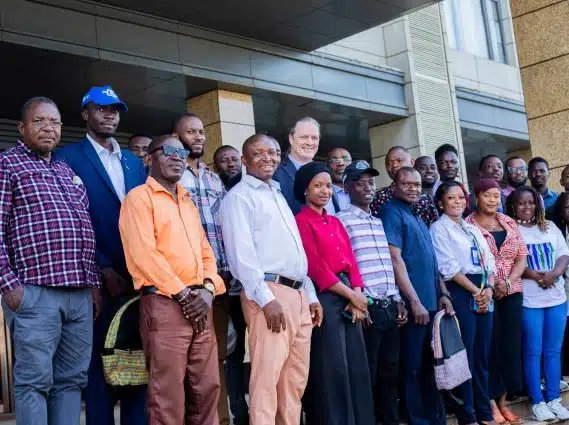 Group of diverse professionals posing together outside a modern building, smiling for a team or community event photo.