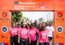 Orange Foundation, SLCB Target Over 5,000 Women in Nationwide Breast Cancer Campaign Group of people wearing pink Breast Cancer Awareness shirts walking under an orange Foundation arch at a charity health walk.
