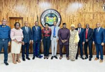 Finance Minister Assures ICASL of Support on Funding and Cooperation Agreement Ten professionals in business attire posing for a group photo in a Ministry of Finance room with a seal on a wood-paneled wall in the background.