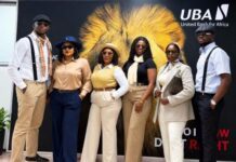UBA Sierra Leone Celebrates Customer Service Week with Five Days of Creativity, Culture and Appreciation Group of six adults in business-casual attire posing in front of a lion backdrop with the UBA logo.