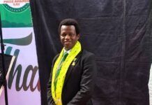 RCBank’s Umaru Abdulsalam Shyllon Earns Prestigious ACIB Qualification Man in a black suit with a lime-green and yellow ceremonial sash posing on a red carpet at an awards event.