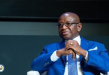 President Bio Calls for Global Investment in Conflict Prevention, Proposes Geneva Commitment to Peace Middle-aged man in a bright blue suit, glasses, and patterned tie, seated with hands clasped.
