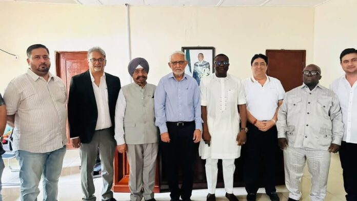 Group of men standing side by side in a room, posing for a photo in smart-casual and traditional attire.