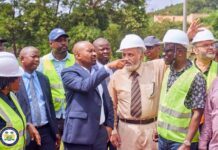 Vice President Inspects BADEA-Funded Project at Milton Margai Technical University Group of construction workers and officials at a site; a man in a blue suit points at a man in a white helmet as others look on
