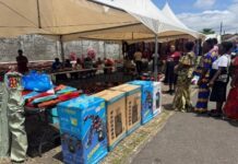 Over 300 Women Receive Free Shopping Items at New Life Ministries’ Conference Outdoor market under white tents with people browsing; boxed electronics lined up on a table and vendors selling items in a busy street scene.