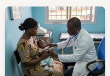One Million Blankets for African Newborns: Angel Care Foundation Expands Initiative to Sierra Leone Doctor using a stethoscope to listen to a baby's heartbeat while the mother holds the infant in a clinic room.