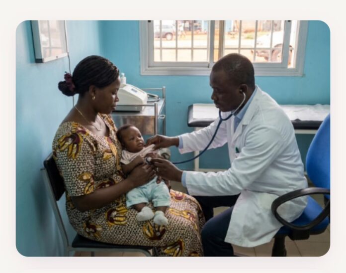 Doctor using a stethoscope to listen to a baby's heartbeat while the mother holds the infant in a clinic room.