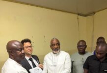 Government Signs Contracts for Four Climate-Resilient Bridges Under US$74 Million World Bank Project Group of men in a formal setting as a certificate is handed from a man in white to another man in white, while others watch and documents lie on the table.
