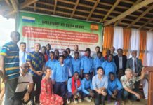 Caritas Freetown, Spanish Ambassador Celebrate Gastronomy and Food Security Partnership Group of students in blue uniforms and adults posing on a stage under a green banner that reads 'Welcome to Casa Leone' with Sierra Leone and Spain flags nearby, likely a welcome event.