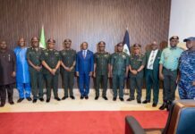 12 Newly Promoted RSLAF Generals Decorated Group of military officers in green uniforms standing with formally dressed civilians in a line, flag backdrop and red carpet.