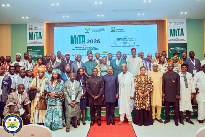 Group photo at the MITA 2026 conference with attendees posing on stage in front of a blue banner showing 'MITA 2026' and event logos.