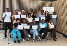 ‘Street Salone Gallery’ Hosts Advanced Street and Documentary Photography Workshop in Freetown Group of diverse people posing with certificates after completing a program in a room with wooden slat walls.