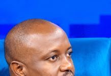 CDP Chairman Victor King Accuses SLPP’s Jimmy Batilo Songa of Interfering in Party Affairs Man wearing a navy blue shirt, speaking with a lavalier mic attached to his collar, seated against a blue backdrop.